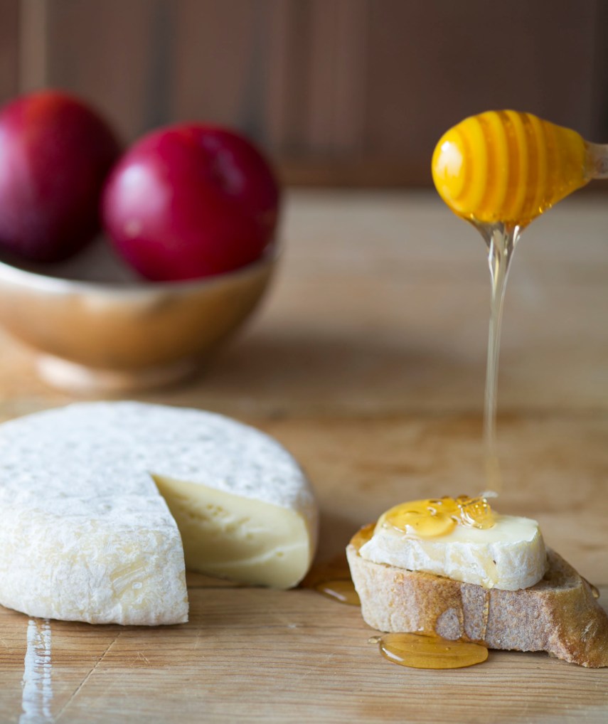 dripping honey on bread, cheese, fruit